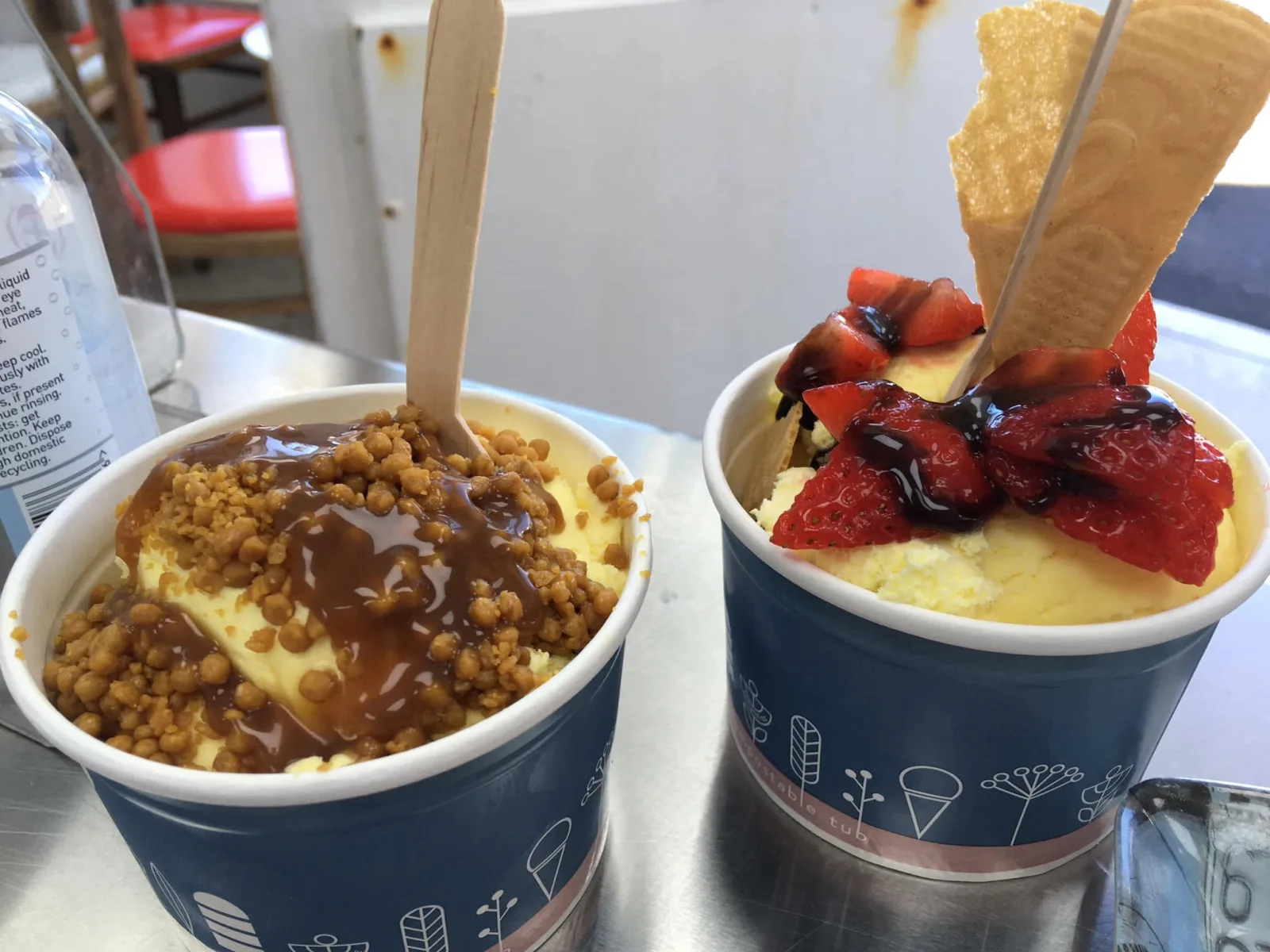 Two Manfredi sundae tubs topped with honeycomb, caramel and fresh strawberries