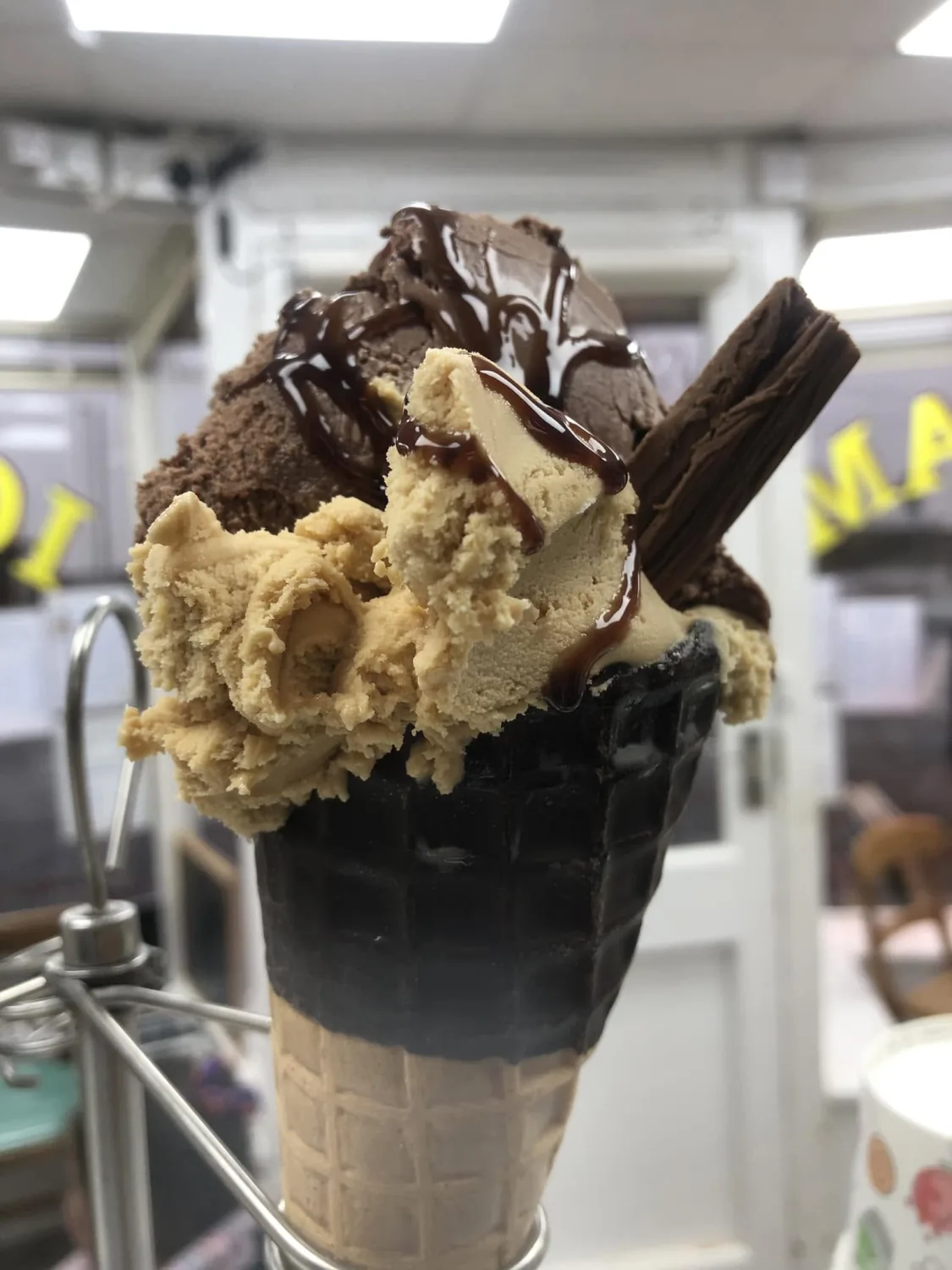 A large chocolate-dipped waffle cone piled with ice cream and a Cadbury Flake